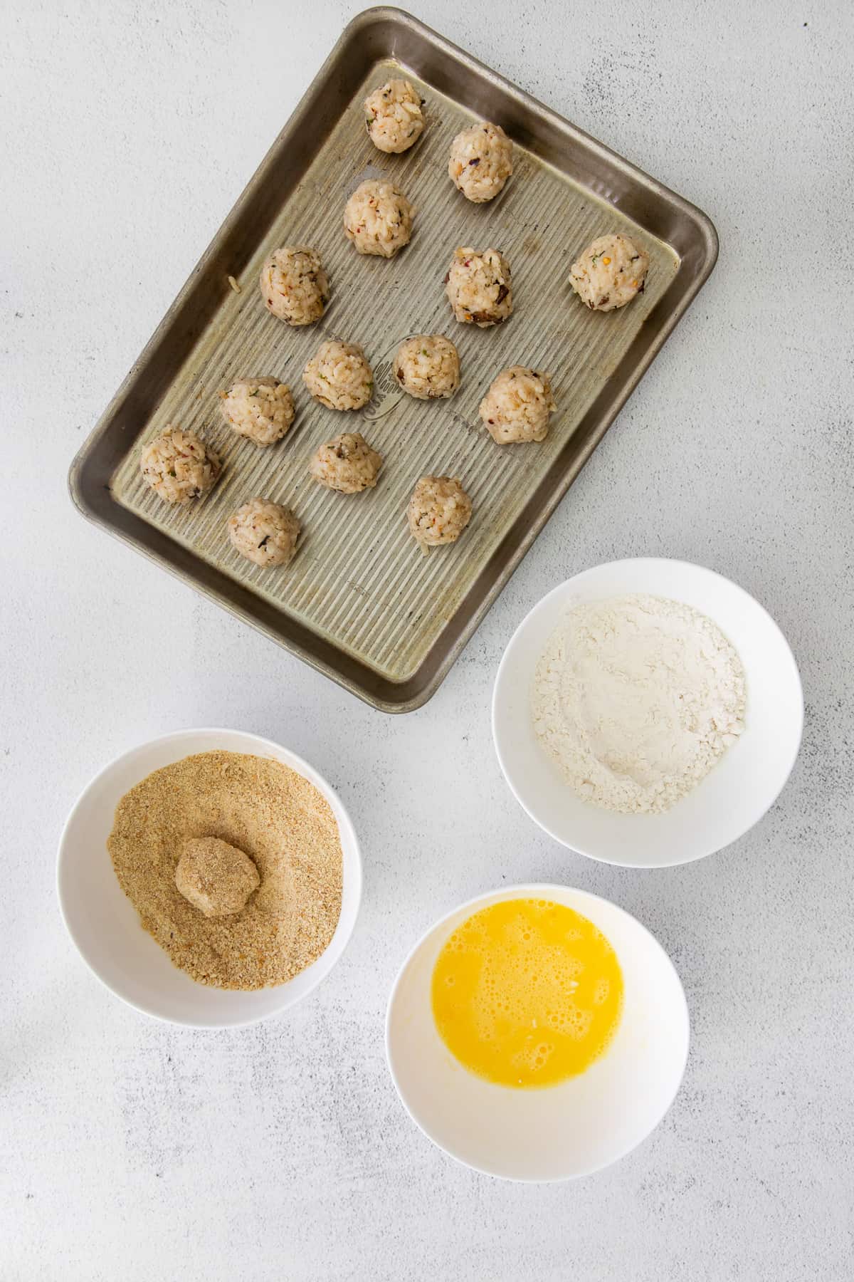 Dipping rice balls into breadcrumbs.