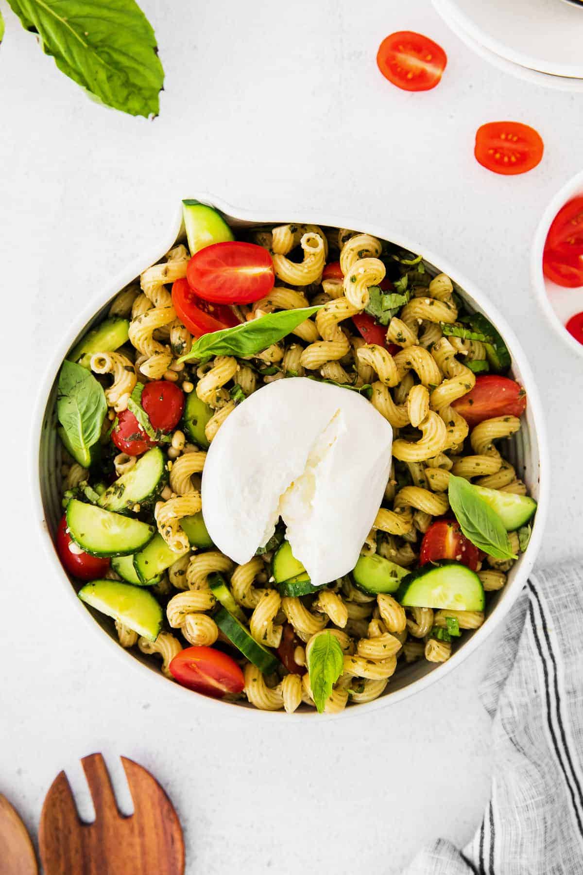 Pesto pasta salad topped with burrata in a bowl.