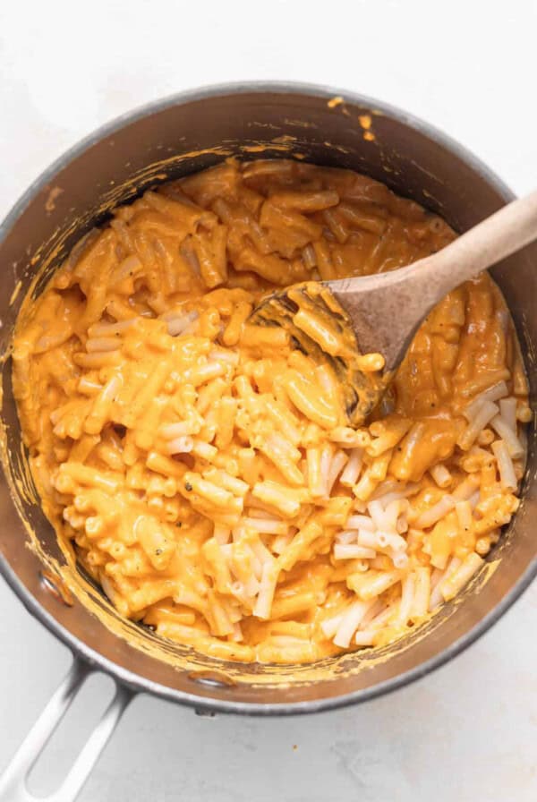 macaroni and cheese in a pan with a wooden spoon.