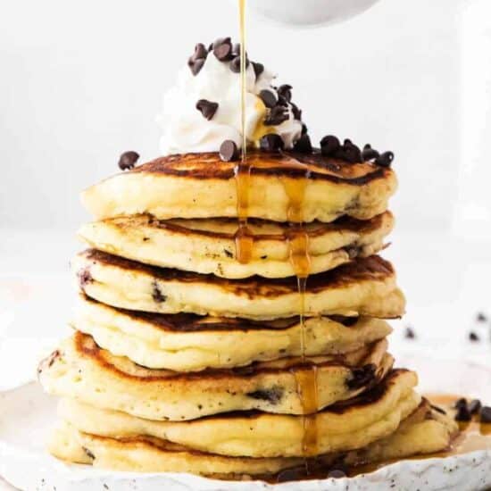 syrup being poured onto chocolate chip ricotta pancakes