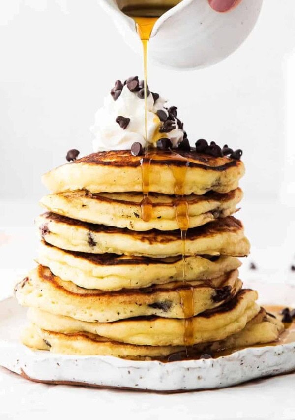 syrup being poured onto chocolate chip ricotta pancakes