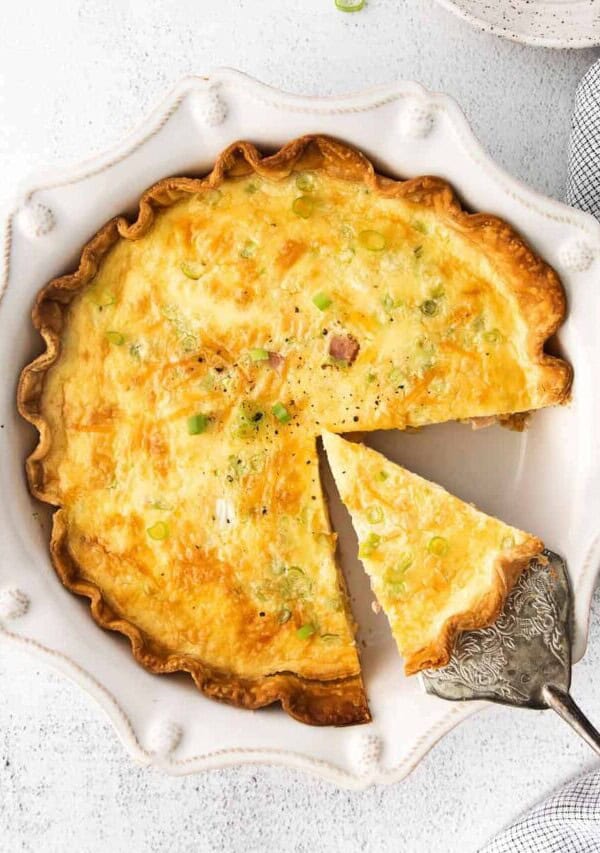 a piece of ham and cheese quiche being removed from pie