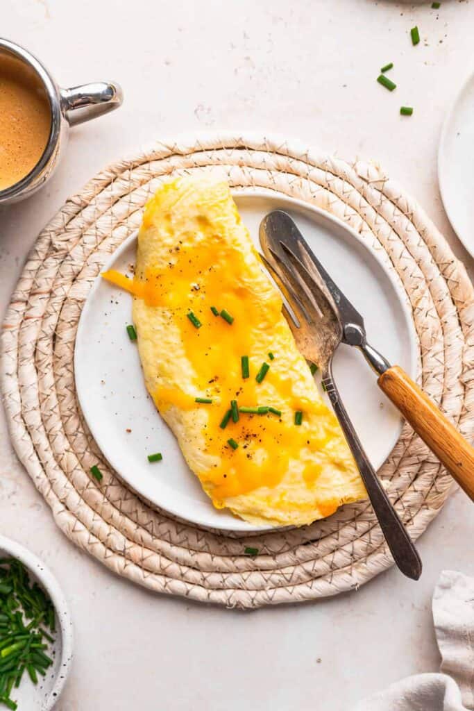 Cheese omelette on a plate topped with fresh chives.