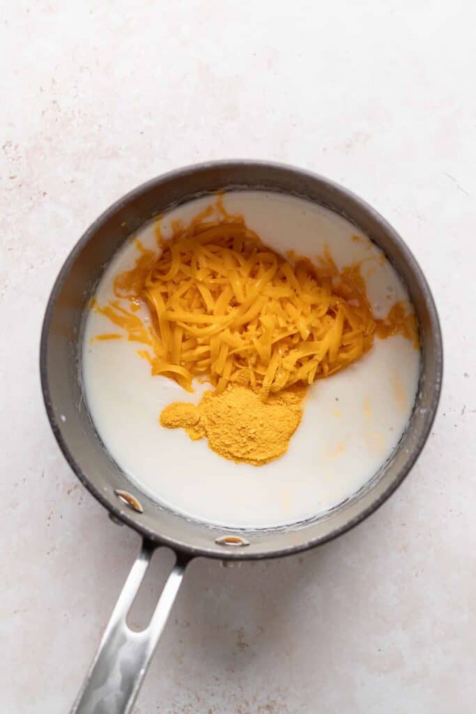 shredded cheese and powdered cheese in a sauce pan with milk