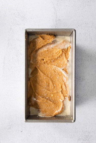 A pumpkin cream cheese bread baked in a pan with a layer of icing.