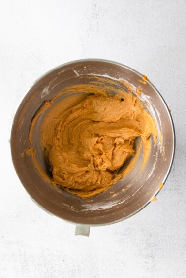 A mixing bowl filled with a pumpkin cream cheese bread mixture.
