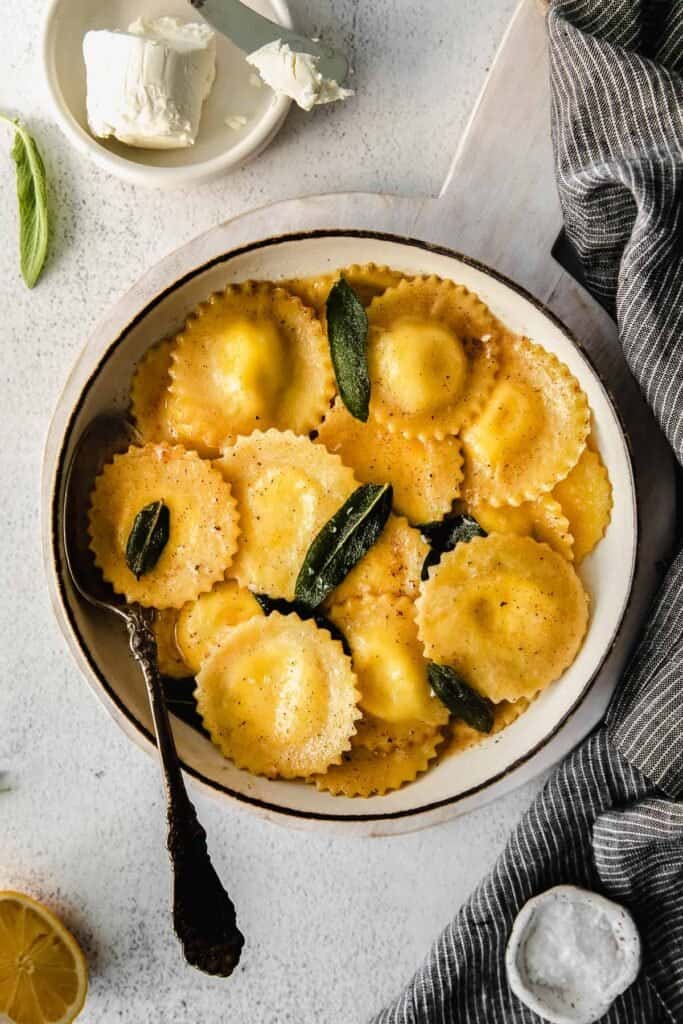 goat cheese ravioli in a bowl topped with sage