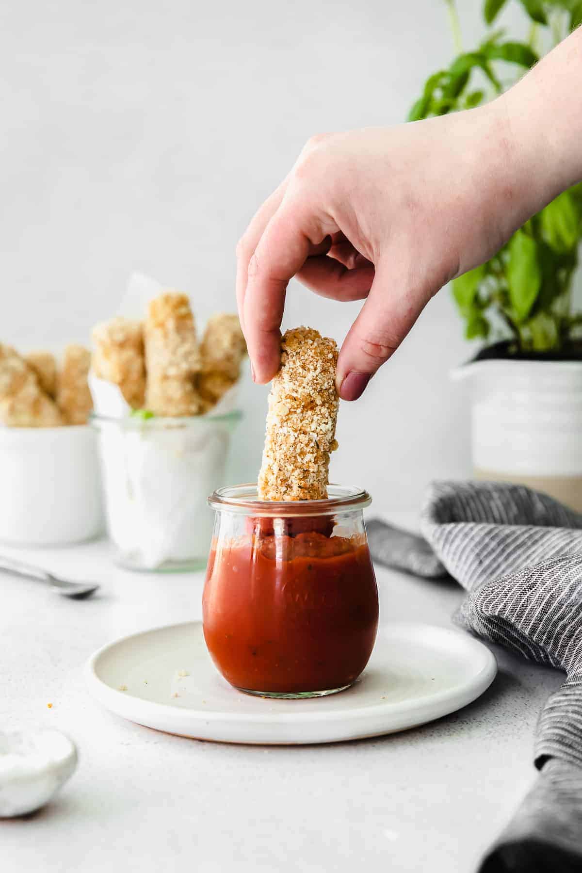 homemade mozzarella stick being dipped into marinara sauce