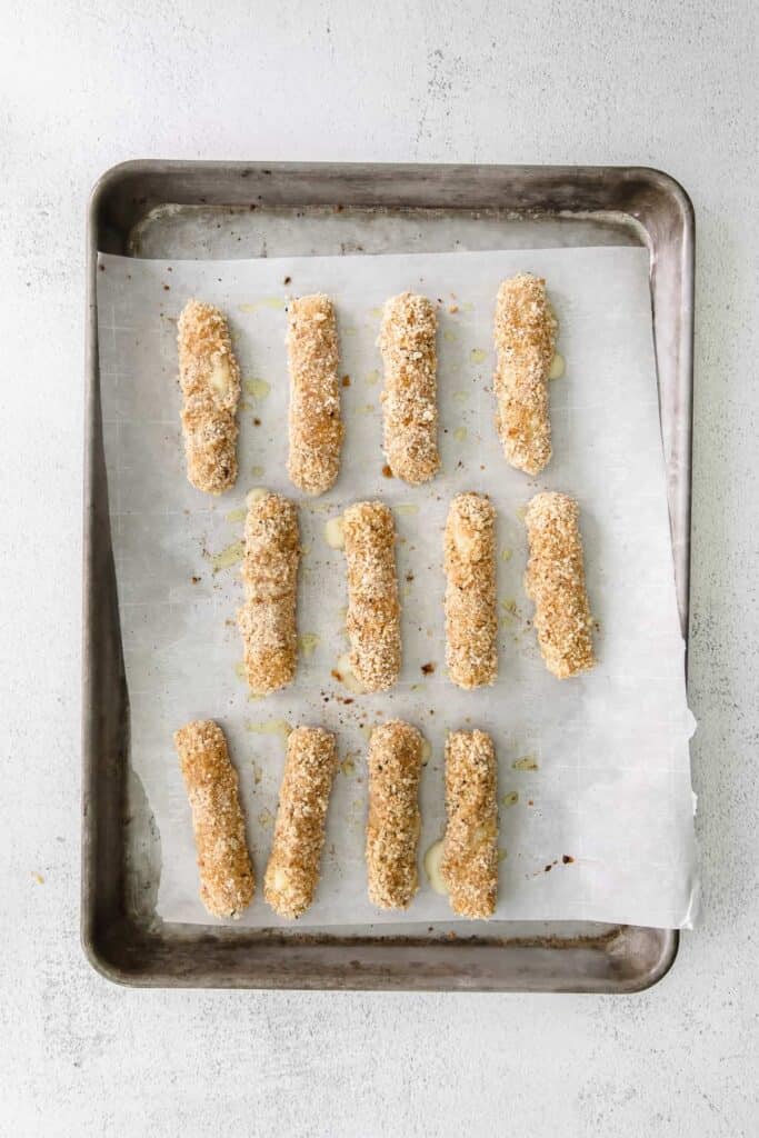 homemade mozzarella sticks on a baking tray lined with parchment paper