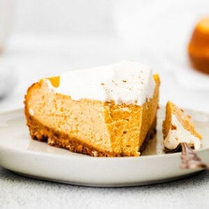 a slice of pumpkin chai cheesecake on a white plate.