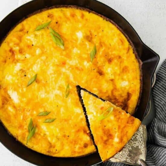 a slice of four cheese frittata being removed from cast iron skillet