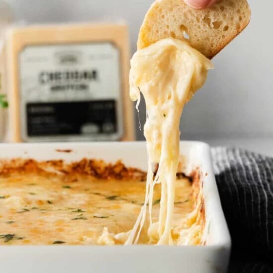 a crostini being dipped into cheese french onion dip