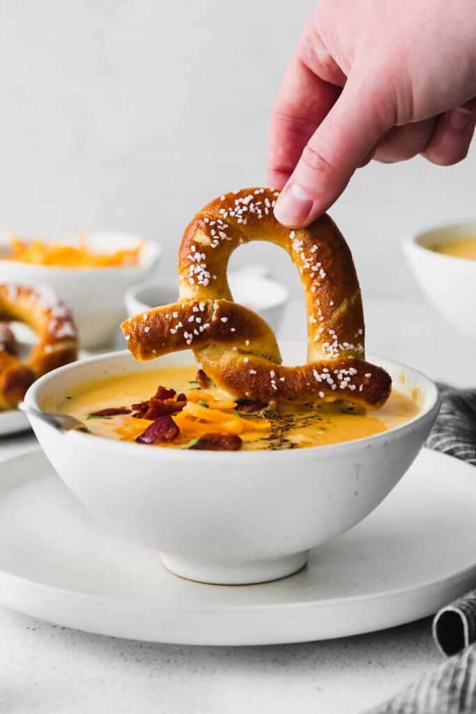 beer cheese soup in a bowl with a soft pretzel being dipped into it