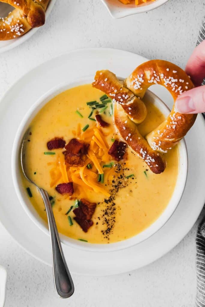 beer cheese soup in a bowl with a soft pretzel dipped in it
