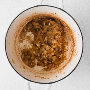 A pot of beer cheese soup with onions on a white background.