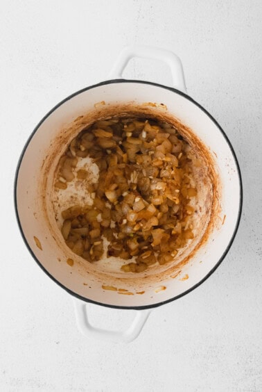 A pot of beer cheese soup with onions on a white background.