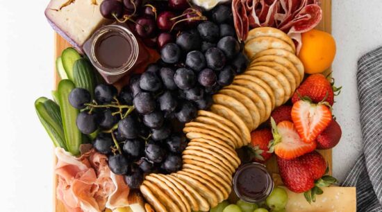 a cheese board with figs, grapes, and crackers.