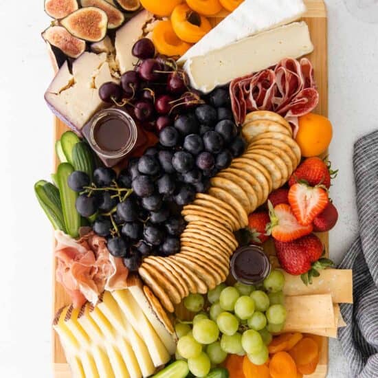 a cheese board with figs, grapes, and crackers.