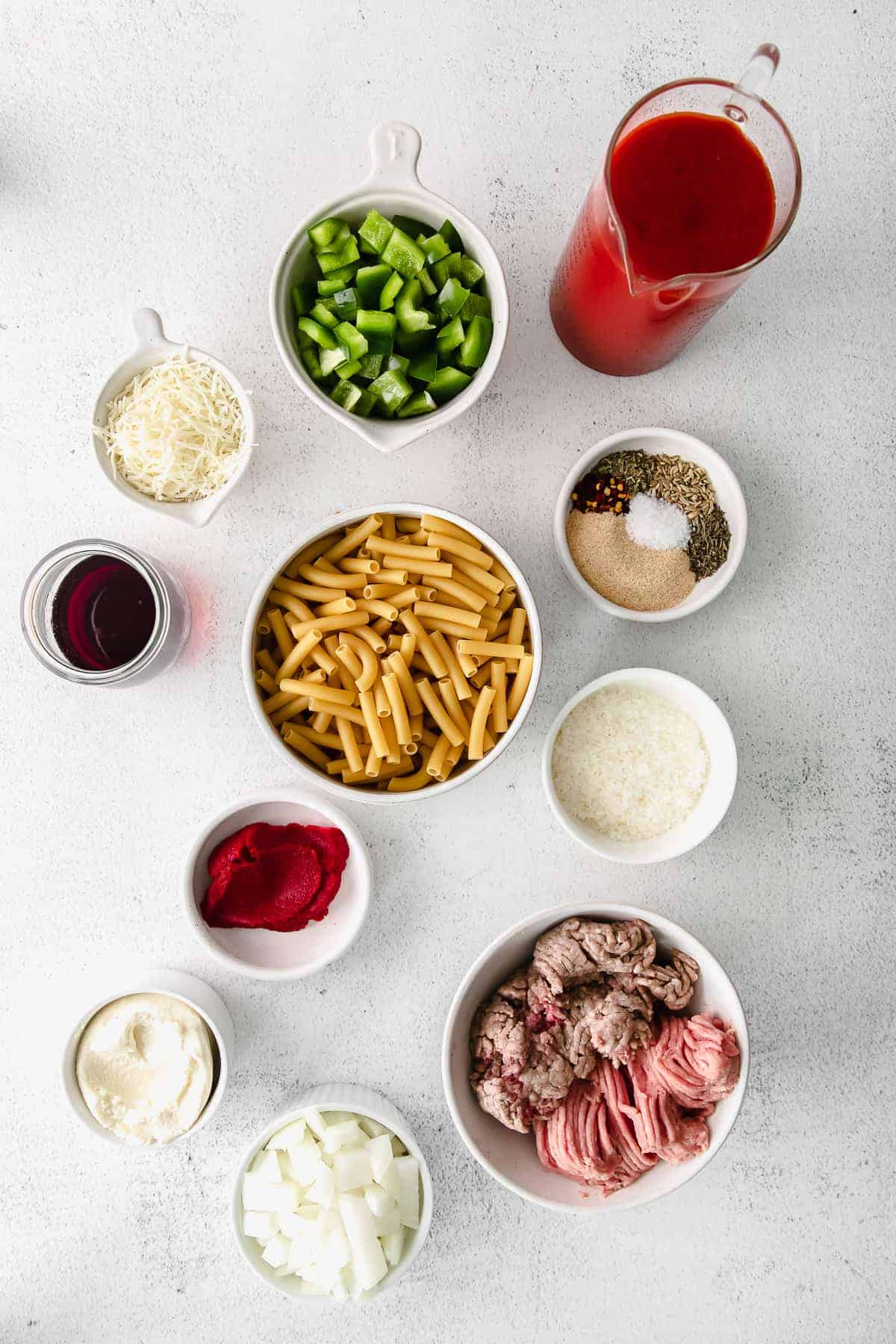 all of the ingredients for baked ziti in small dishes on the counter top. 