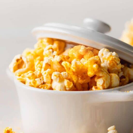 cheesy popcorn in a white bowl.