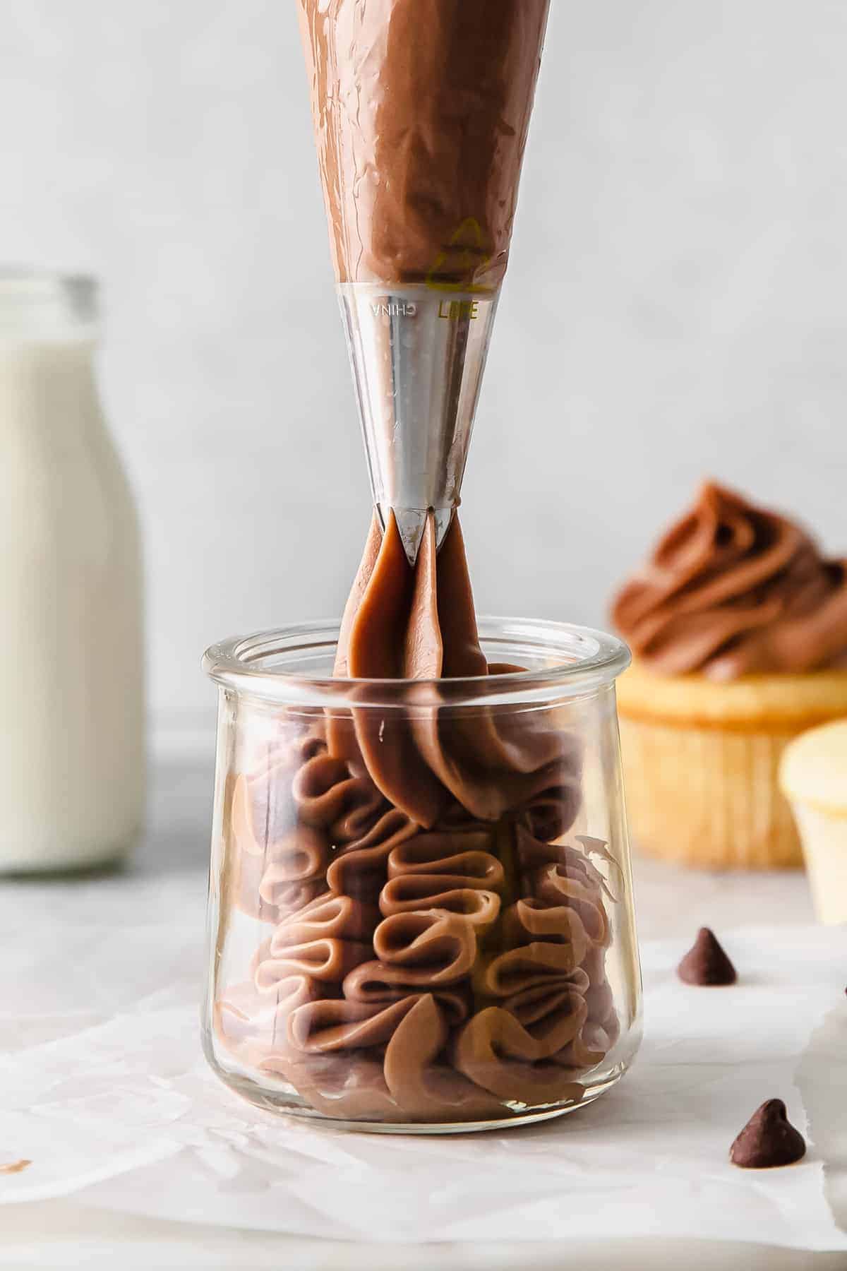 Pipping chocolate cream cheese frosting into a jar. 