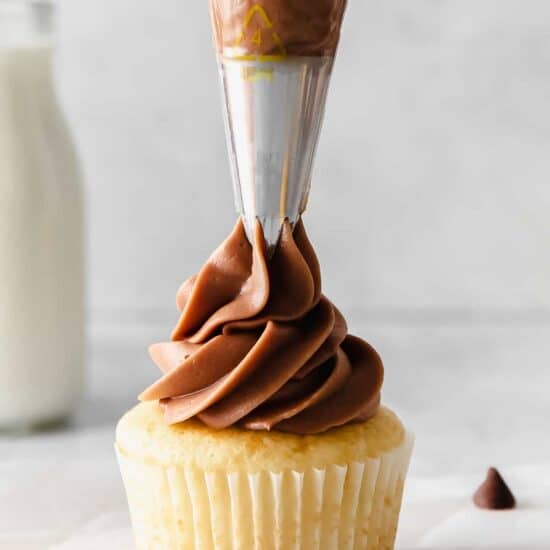 a chocolate frosting being poured onto a cupcake.