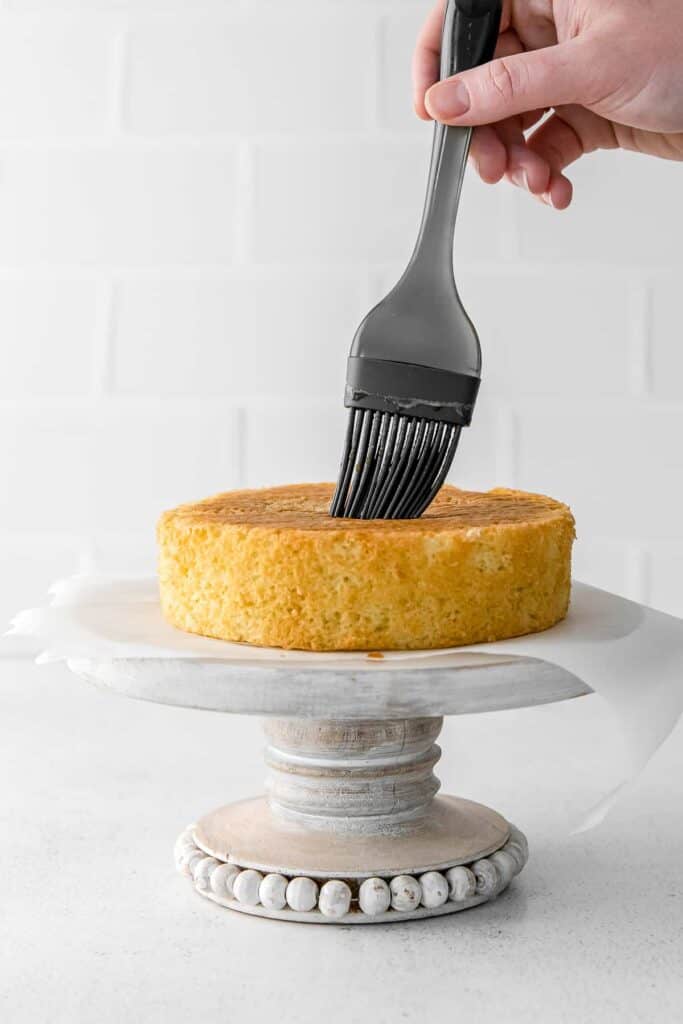 silicone brush brushing espresso over layer cake