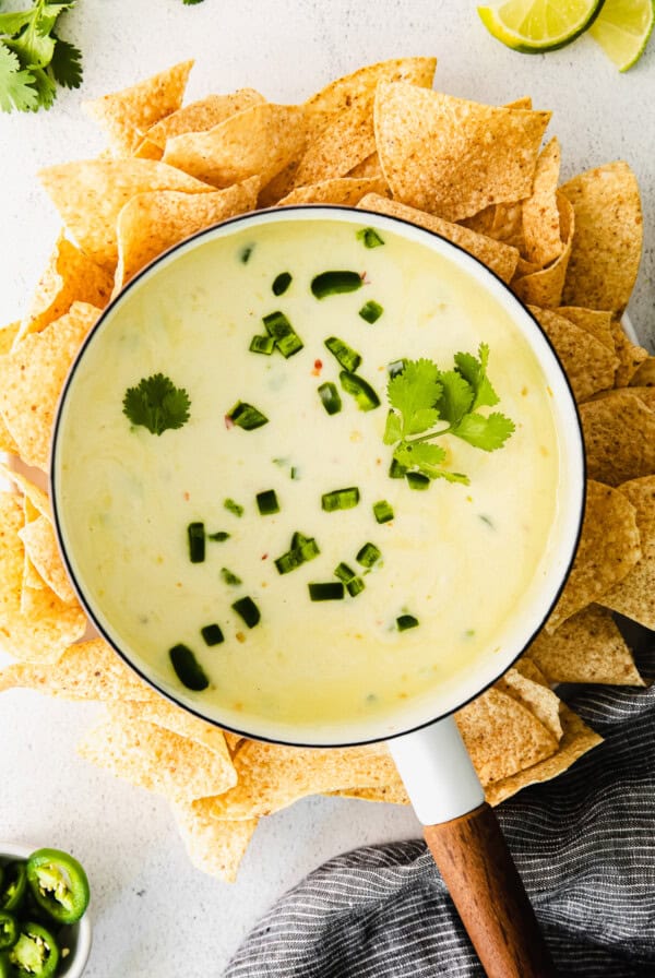 a bowl of homemade guacamole with tortilla chips and limes, accompanied by queso dip.