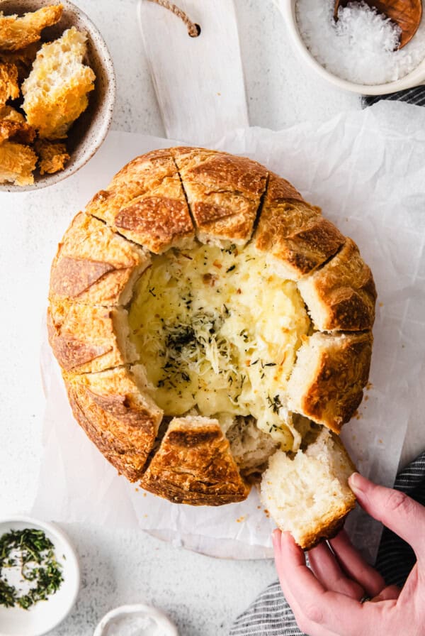 a person taking a bite out of a bread with cheese in it.