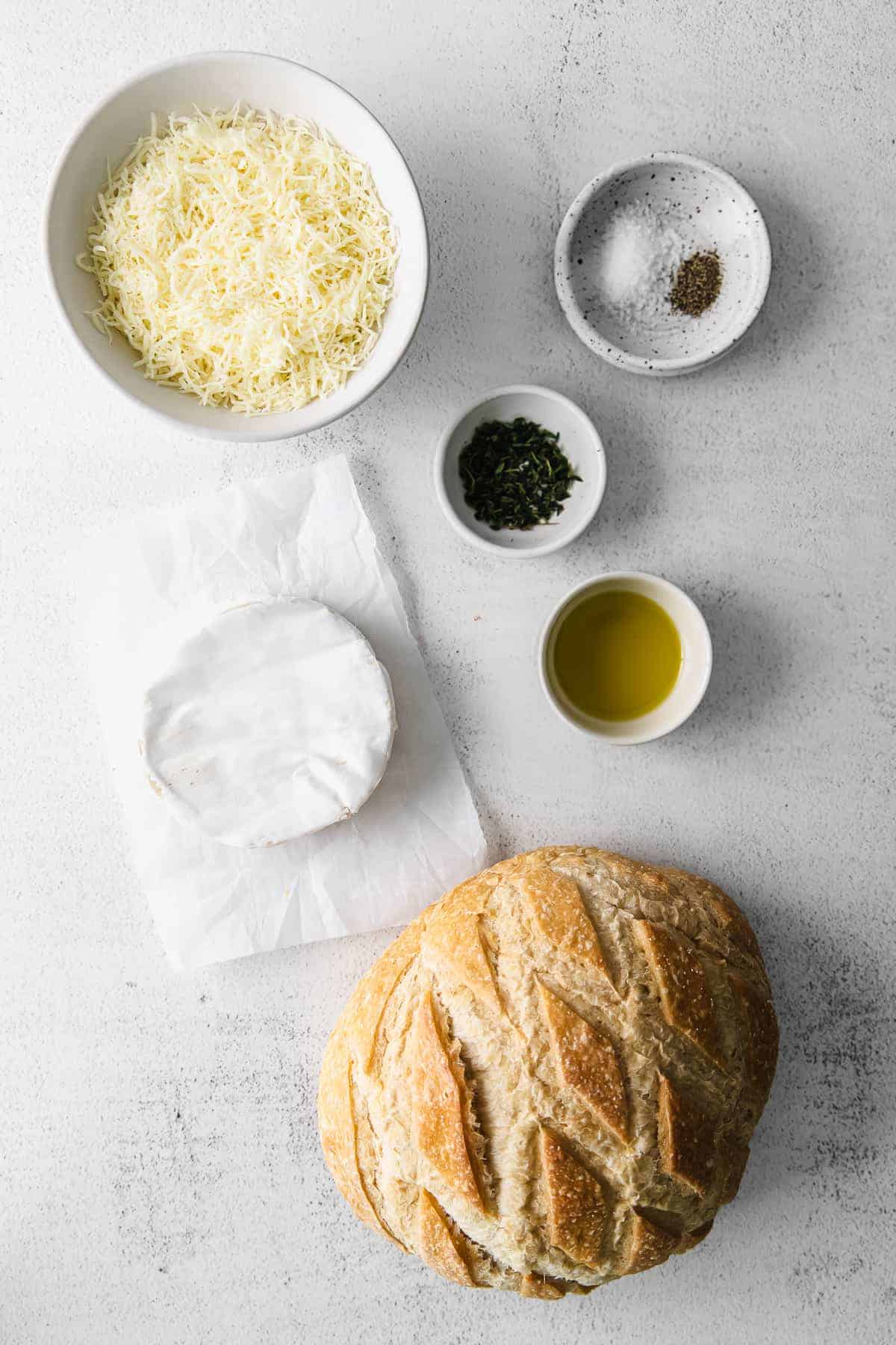 Sourdough baked brie is a fun twist on classic baked brie. Bake the brie inside a fresh loaf of sourdough and use the sides to scoop the cheesy deliciousness. ingredients on countertop