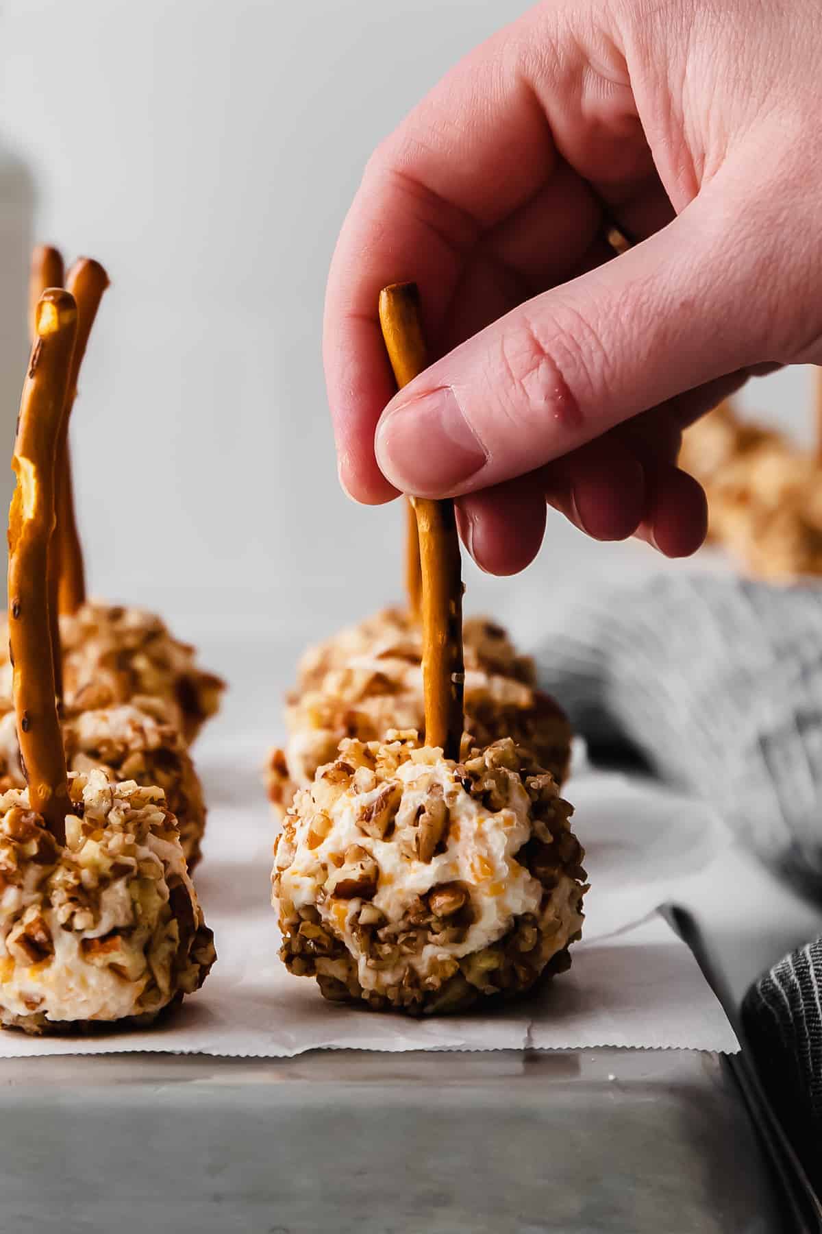 a hand grabbing a cheese ball bite off a plate