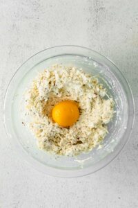 an egg in a glass bowl resting on a white background.