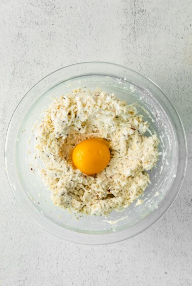 an egg in a glass bowl resting on a white background.