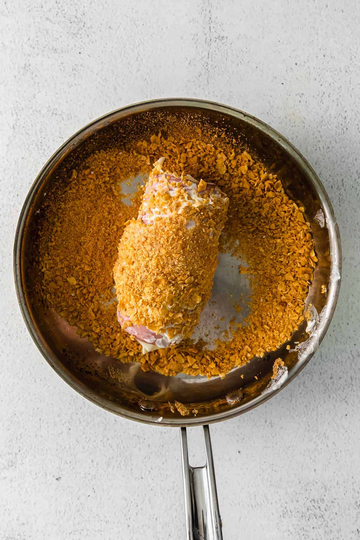 chicken cordon bleu being rolled in corn flakes for the breading