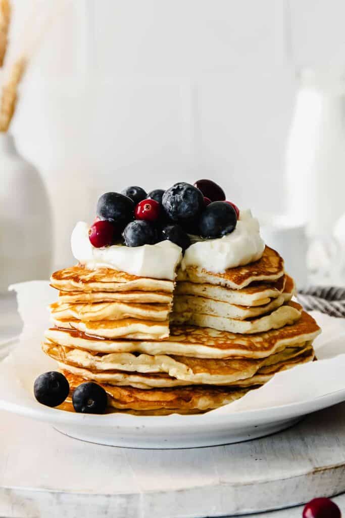 stack of cream cheese pancakes topped with berries and yogurt