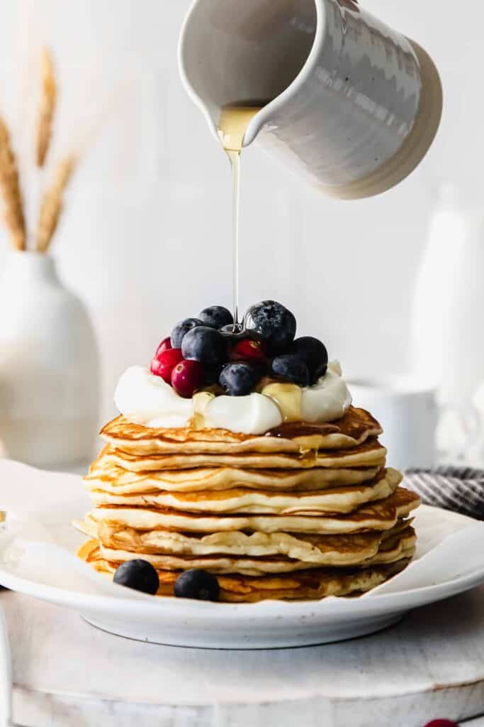 maple syrup being poured over cream cheese pancakes