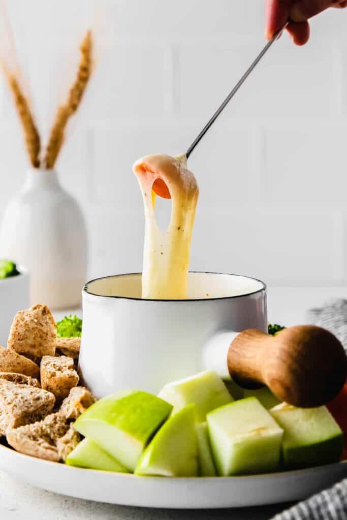 Dipping a carrot in cheese fondue. 