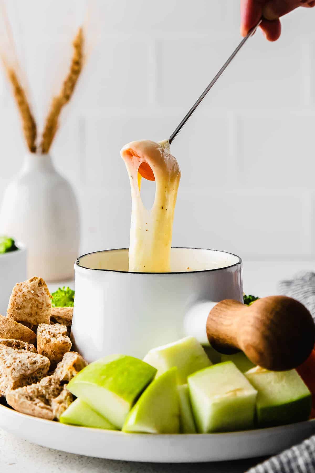 Dipping a carrot in cheese fondue. 