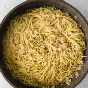 a pan full of pasta with garlic and onions.