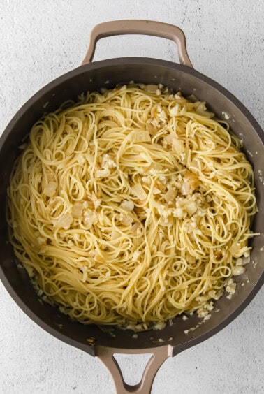 a pan full of pasta with garlic and onions.