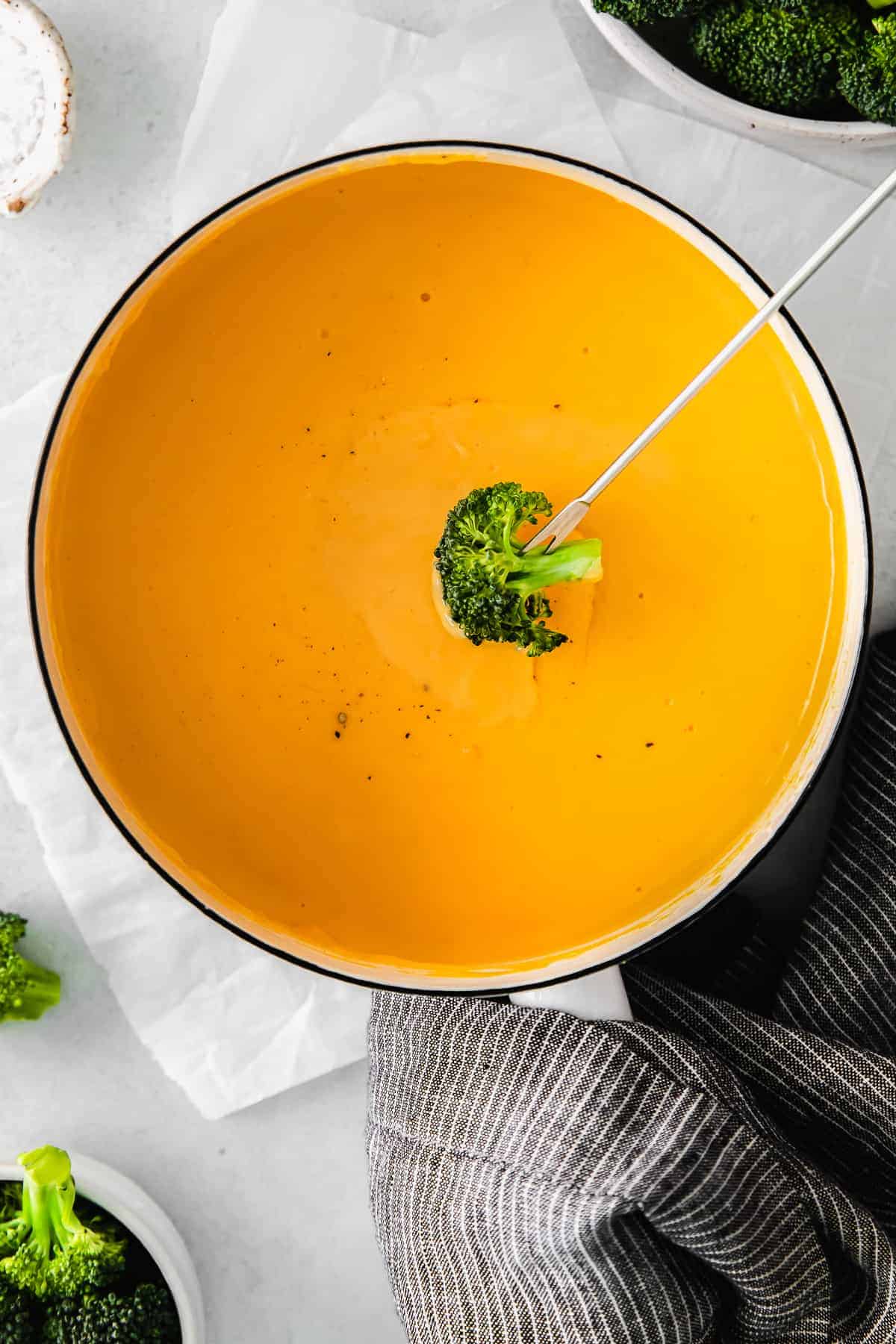 Dipping a broccoli floret into cheese sauce. 