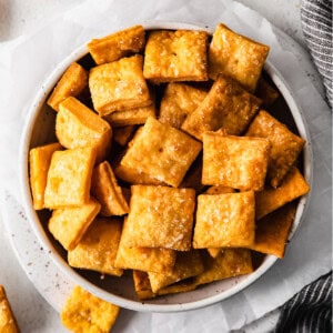 cheesy crackers in a bowl next to a napkin.