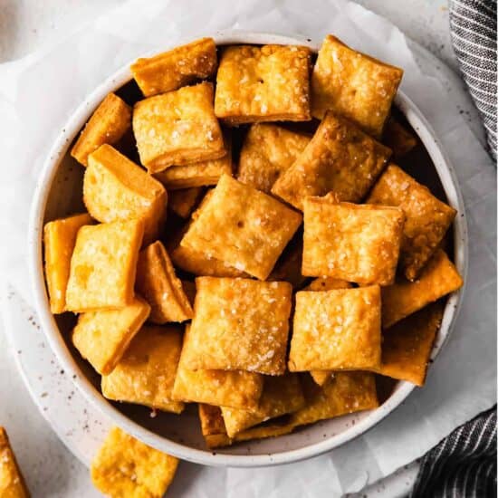 cheesy crackers in a bowl next to a napkin.