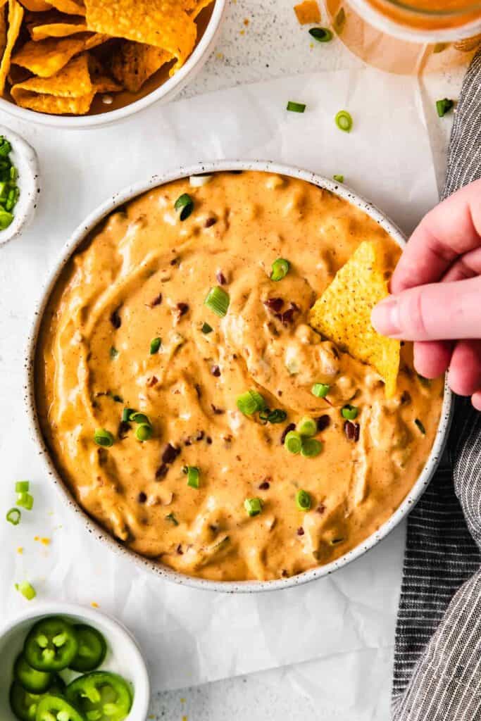 chili cheese dip in a bowl with a tortilla chip