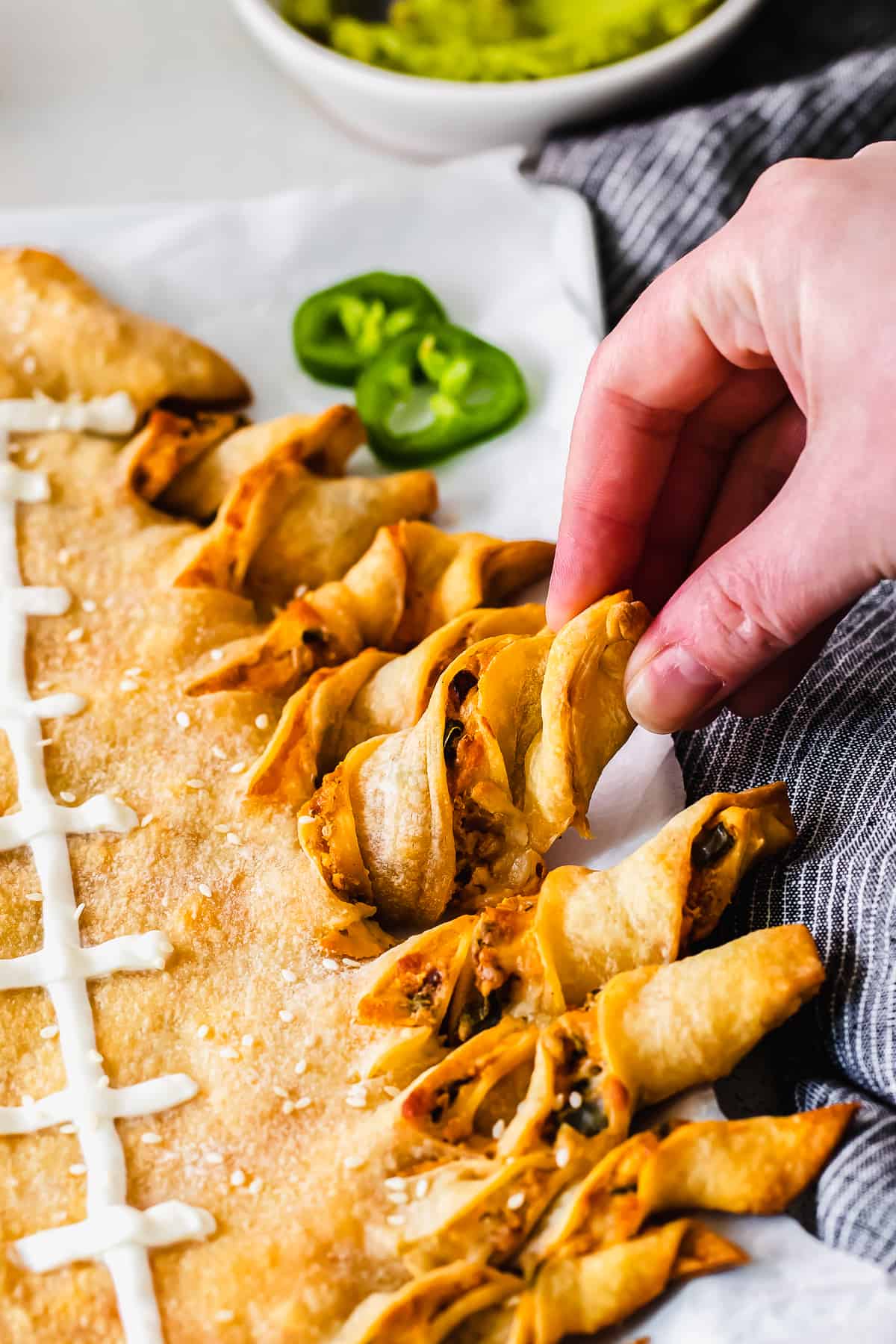 hand pulling off a cheesy breadstick from the football