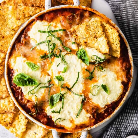 cheesy cheesy dip in a white bowl surrounded by crackers.