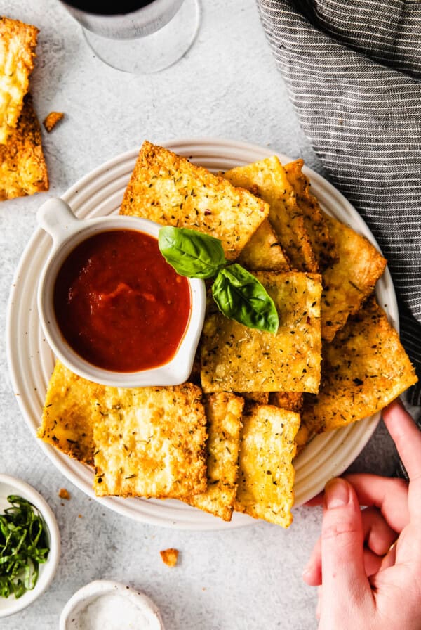 a plate of cheesy crackers with dipping sauce and a glass of wine.