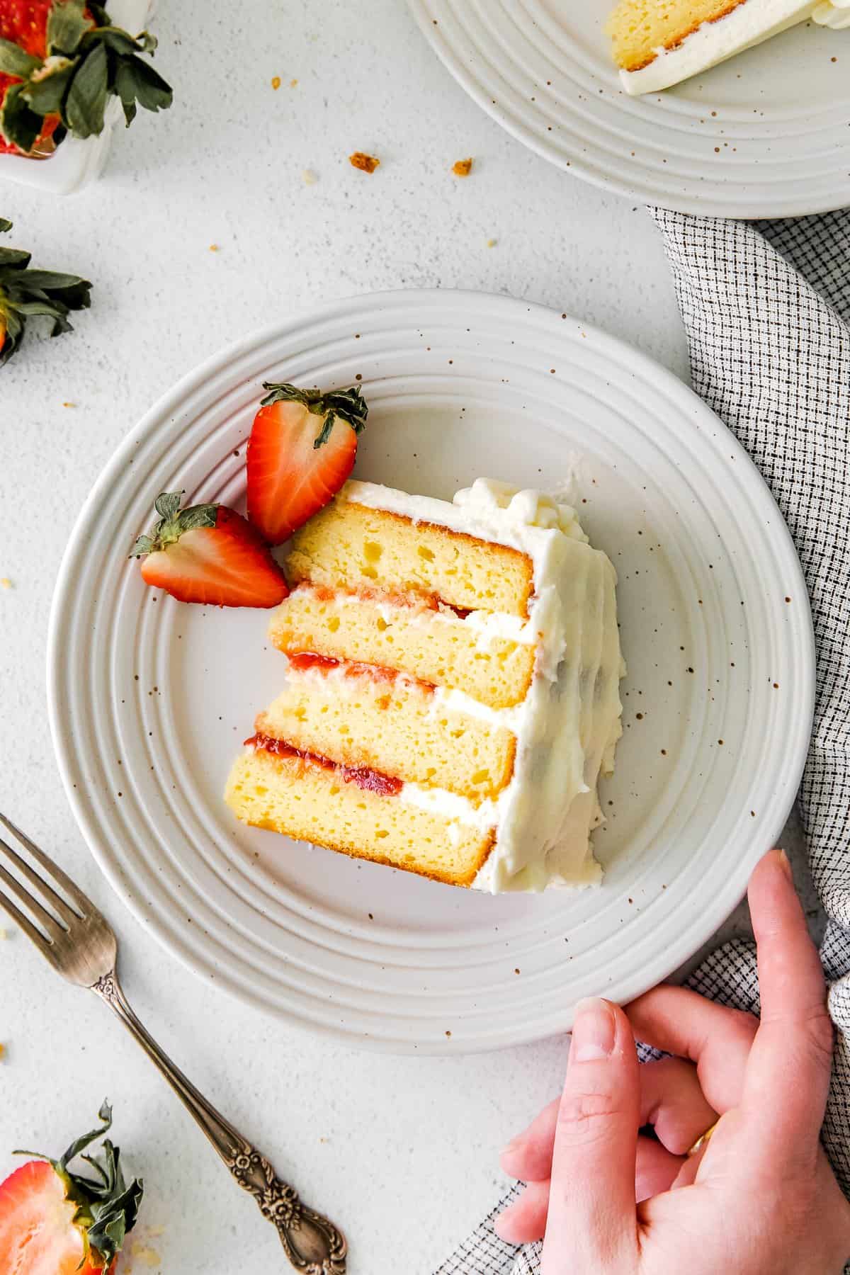 A fork taking a bite out of a piece of ricotta cake. 