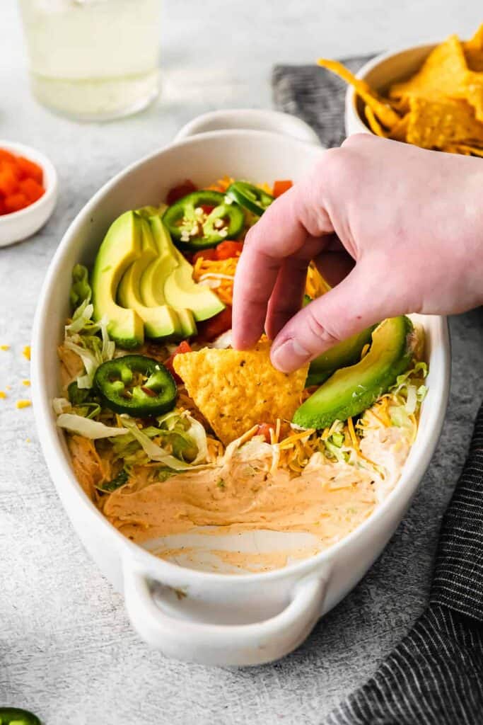 tortilla chip being dipped into a bowl of taco dip