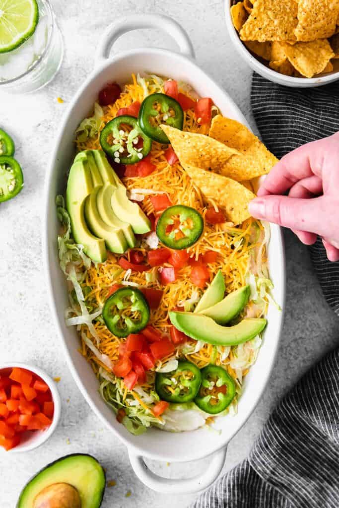 taco dip topped with avocado slices and fresh jalapenos